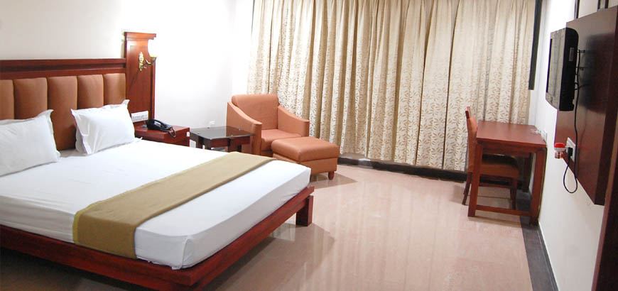 A guest room with the bed made and curtains drawn back.