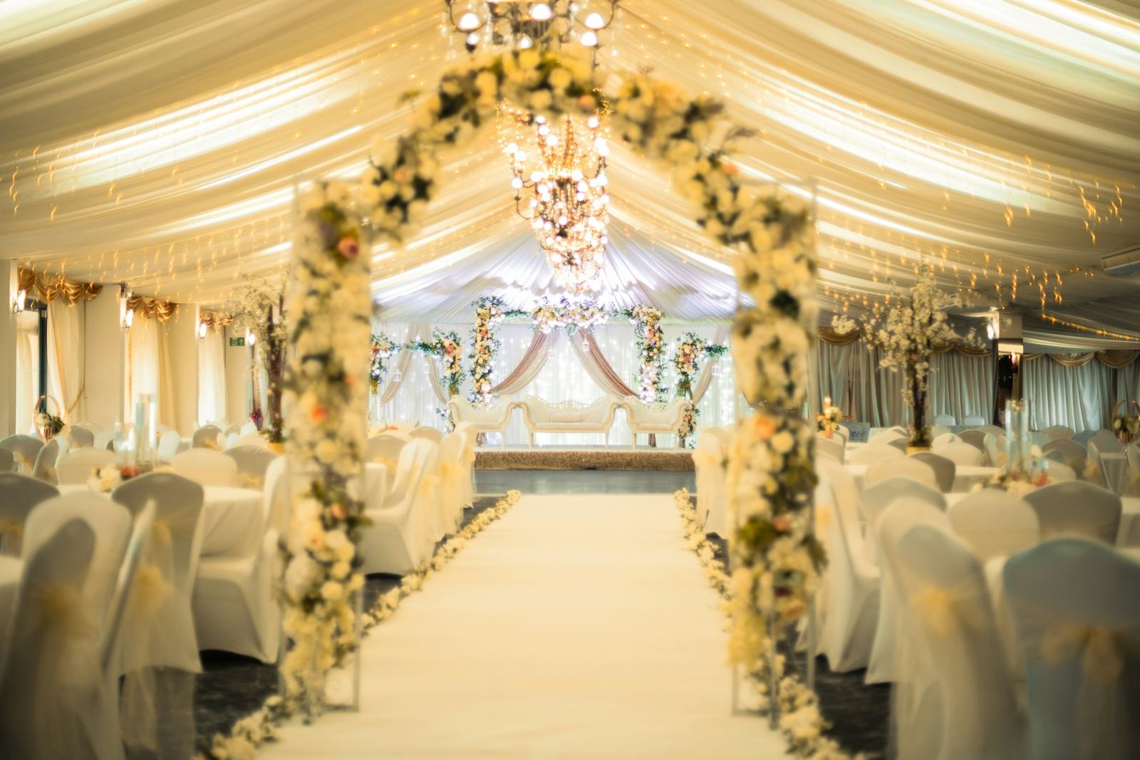 A banquet hall laid out with round tables and floral centrepieces.