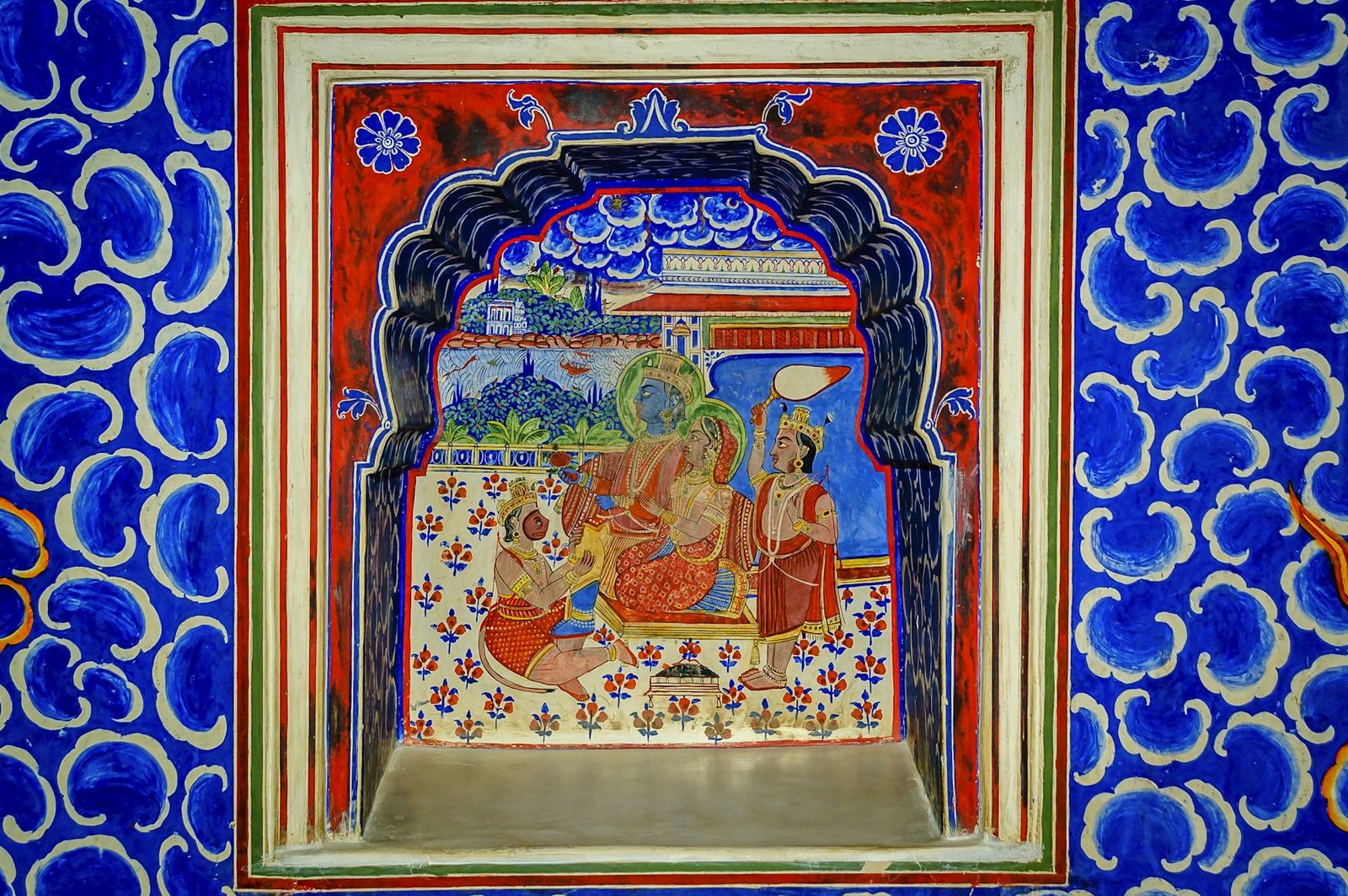 A hand-painted Rajasthani mural set into a blue patterned wall.